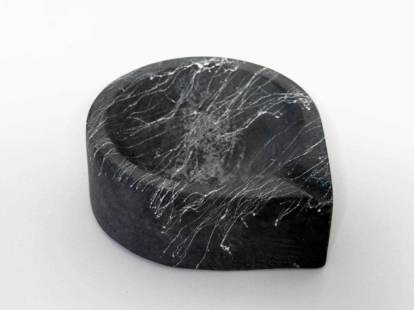 Aschenbecher TROPFEN schwarz, Marmorierung weiß, Betonmischung, bruchsicher und solide Formgebung, weiß, jeder Aschenbecher ist ein Unikat! Während der handgemachten Gestaltung kann der Grundfarbton und Struktur abhängig vom Mischverhältnis von dem im Foto abgebildeten Aschenbecher gering abweichen. Das Gewicht variiert um zwischen 205-260 gr. Größe (gemessen am Umkarton der Verpackung): L/B/H 10,2 cm X 10,2 cm X 3,7 cm Katalogpreis=7,99€